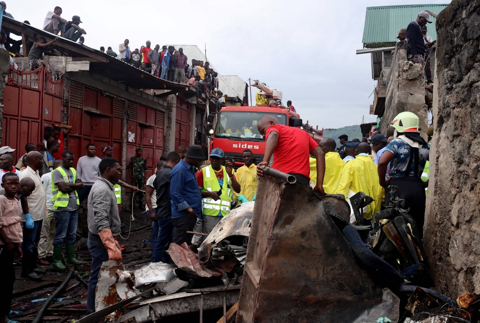 Rescuers and civilians gather at the site where a Dornier 228-200 plane operated by local company Busy Bee crashed into a densely populated neighborhood in Goma