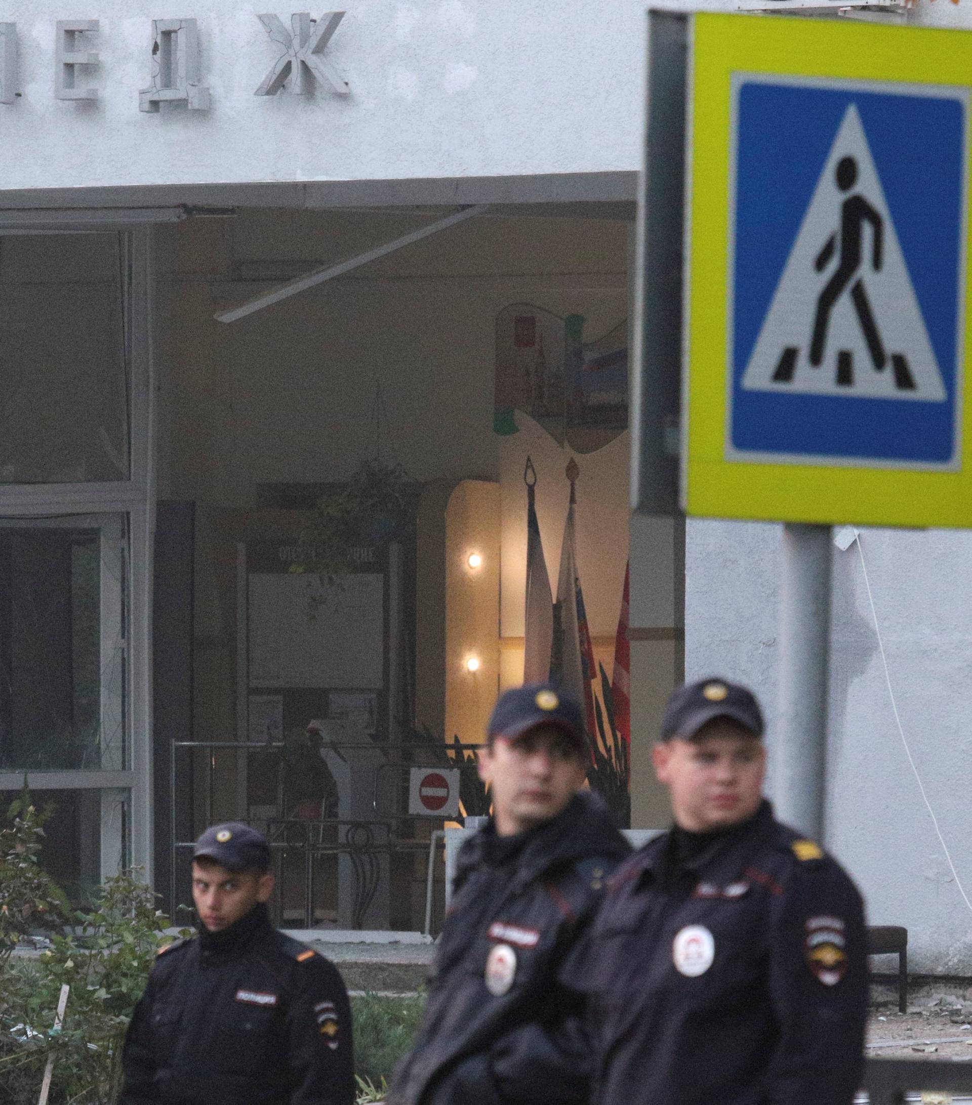 Russian policemen gather outside the damaged building of a college following a recent attack in Kerch