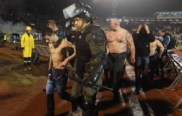 Police escort the soccer fans injured during the fights at a match between Red Star and Partizan in Belgrade