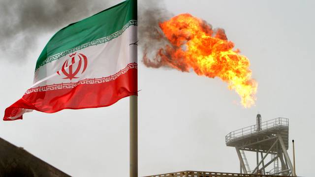 FILE PHOTO: A gas flare on an oil production platform in the Soroush oil fields is seen alongside an Iranian flag in the Persian Gulf