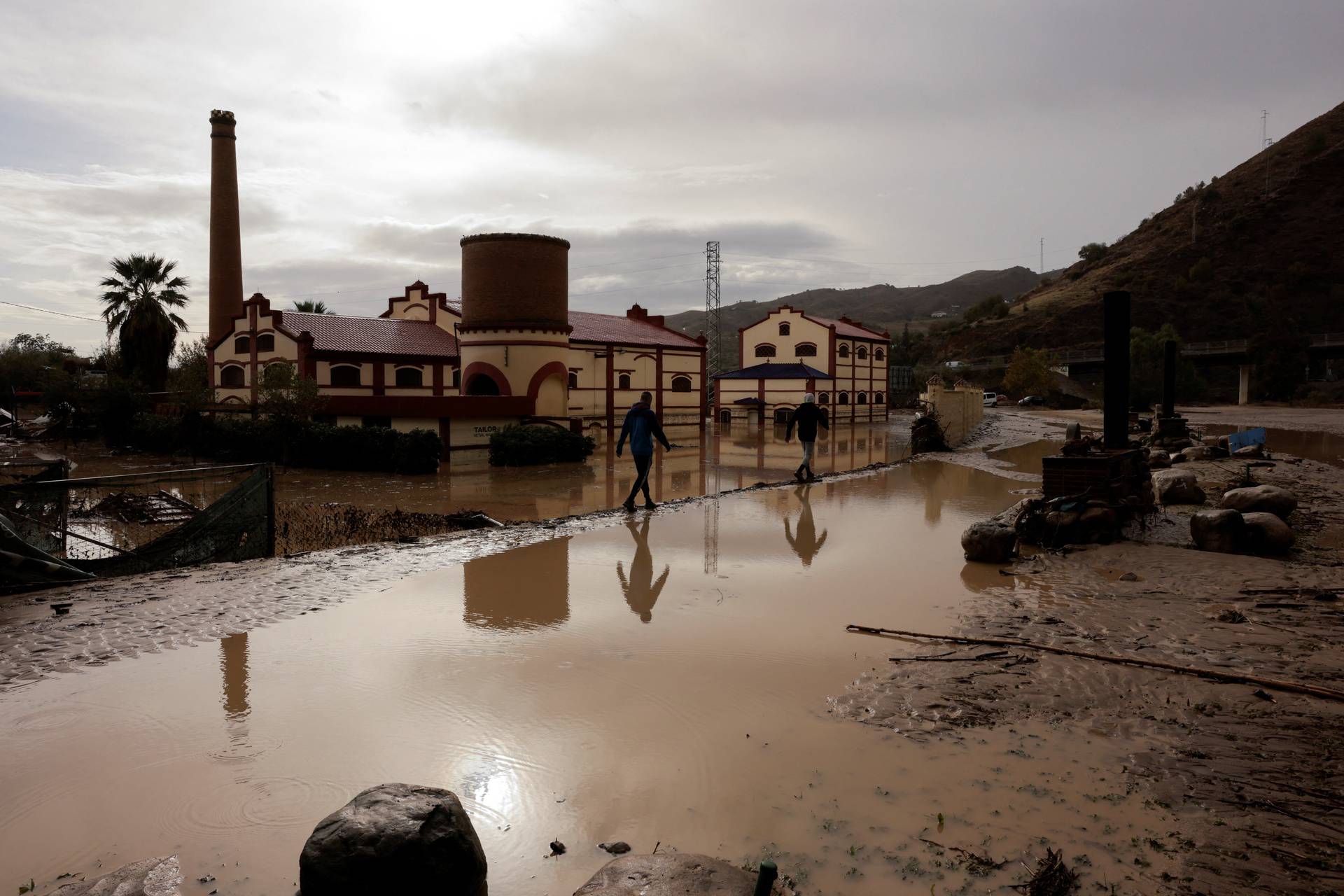 Men walk along a flooded area after heavy rains and floods in Alora