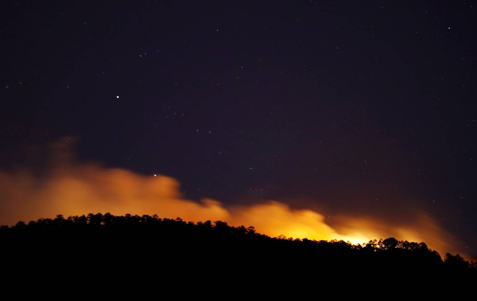 Flames and smoke are seen as a forest fire advances on a mountain in Arico, on the Canary island of Tenerife