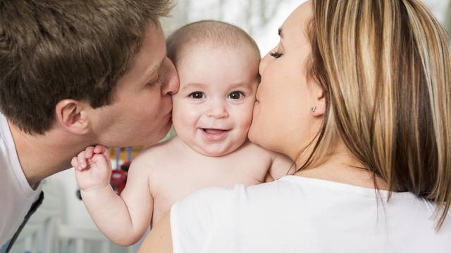 Closeup portrait of young parents kissing beautiful newborn son