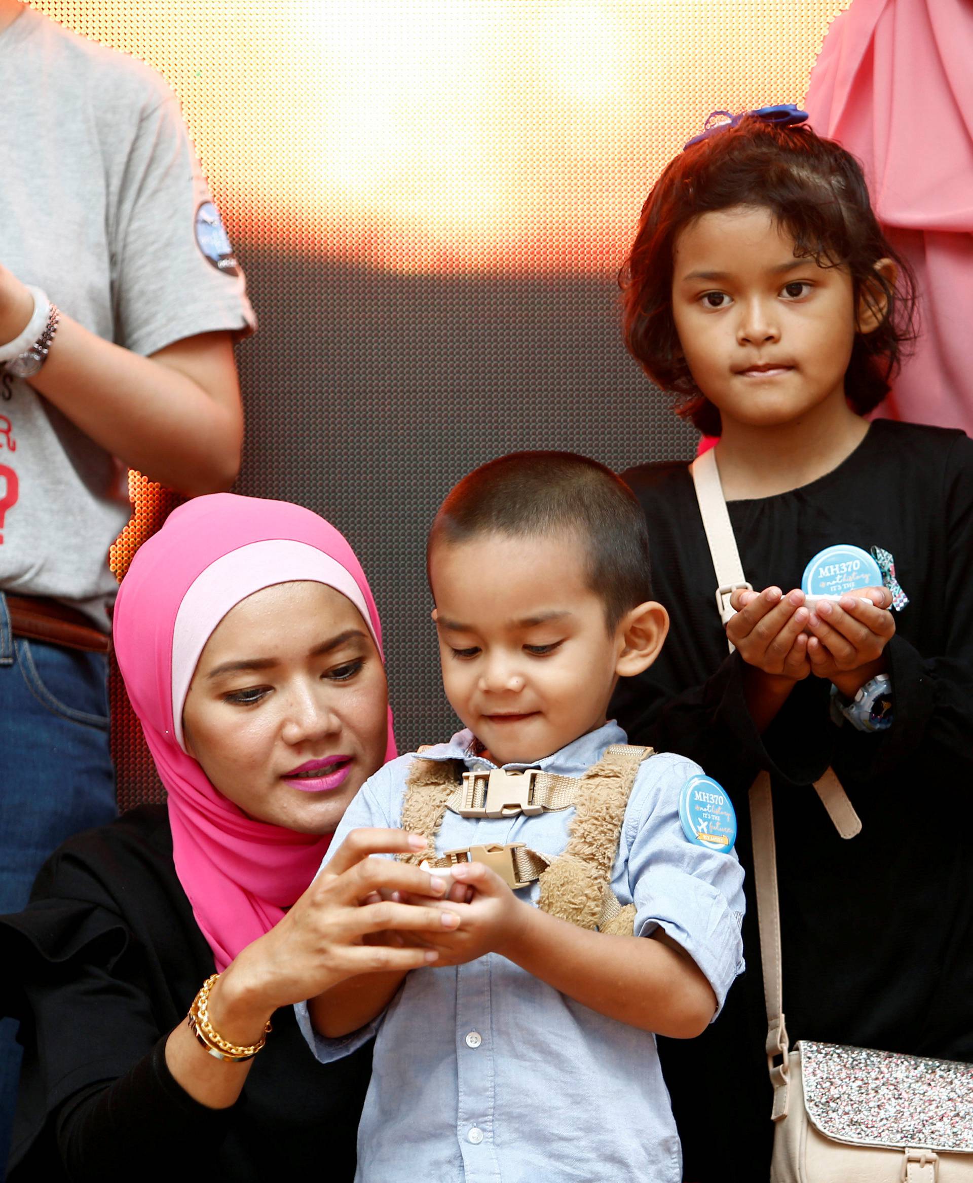 Malaysia Airlines flight MH370 flight attendant, Mohamad Hazrin Hasnan's wife, Intan, and children hold candles during its fourth annual remembrance event in Kuala Lumpur
