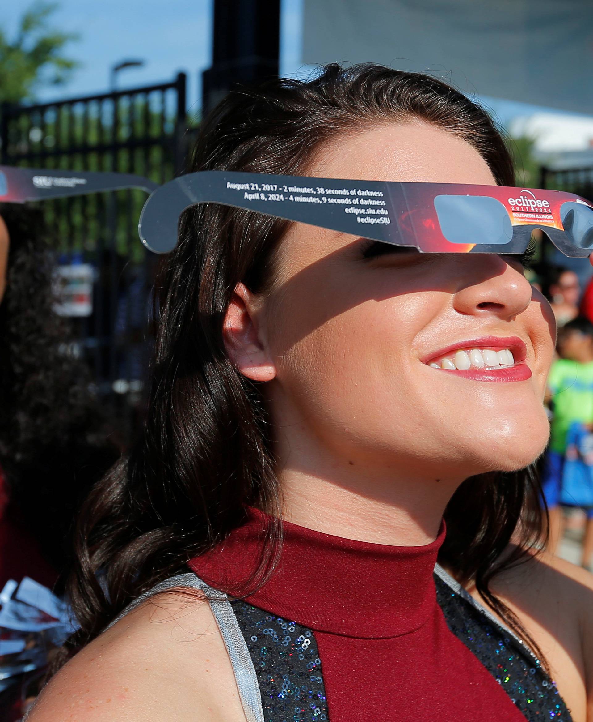 Cheerleaders use solar viewing glasses before welcoming guests to the football stadium to watch the total solar eclipse at Southern Illinois University in Carbondale