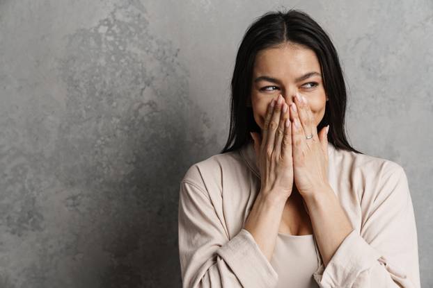 Brunette hispanic woman looking aside and covering her mouth