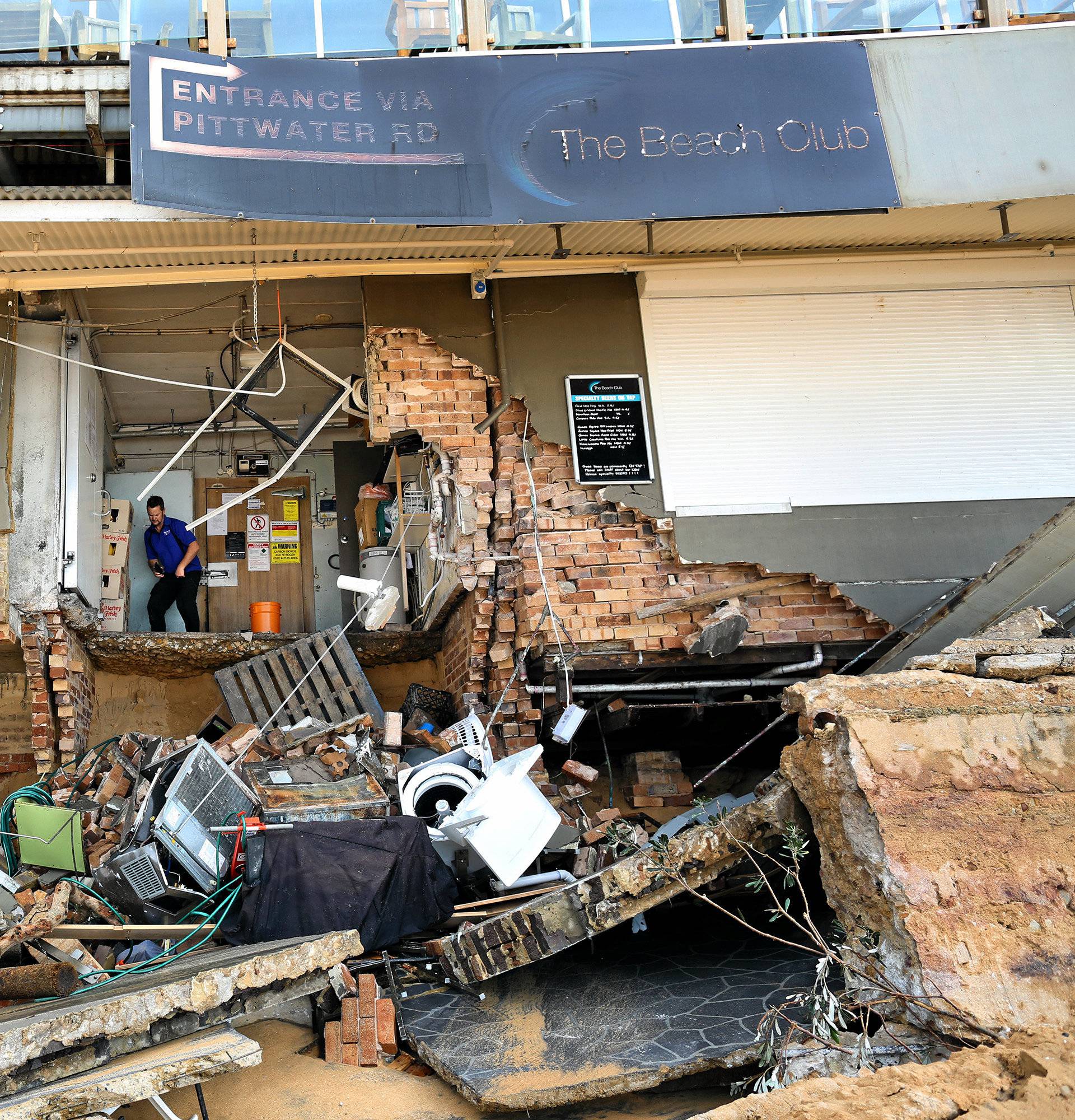 A man stands inside an area of The Beach Club after it was damaged by severe weather, which brought strong winds and heavy rain to the east coast of Australia, at Collaroy beach in Sydney