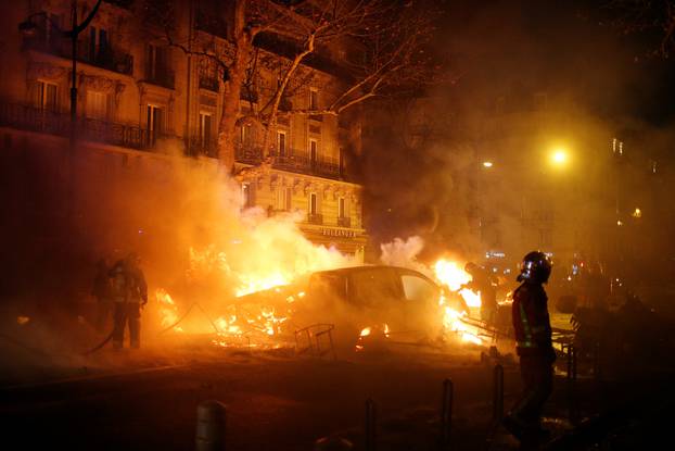 Firemen extinguish burning cars set afire by protesters wearing yellow vests, a symbol of a French drivers