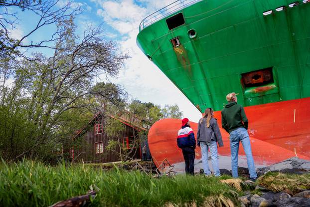 People stand near a container ship, which almost hit a house, in Trondheim