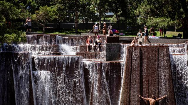 People cool off in a public fountain during hot weather in Portland