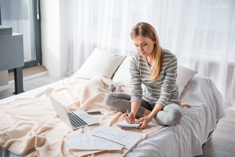 Focused female writing in pad near infant