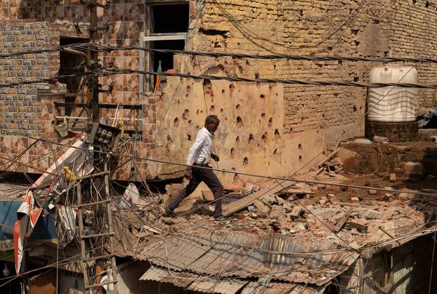A man walks amidst debris on the roof of a damaged house, following Pakistan's military operation against India, in Rehari, Jammu
