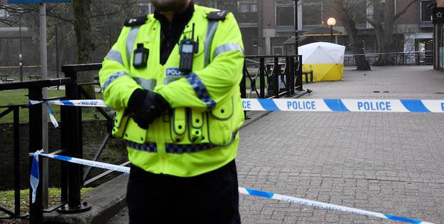 Police officers stand at crime scene tape, as a tent covers a park bench on which former Russian inteligence officer Sergei Skripal, and a woman were found unconscious after they had been exposed to an unknown substance, in Salisbury