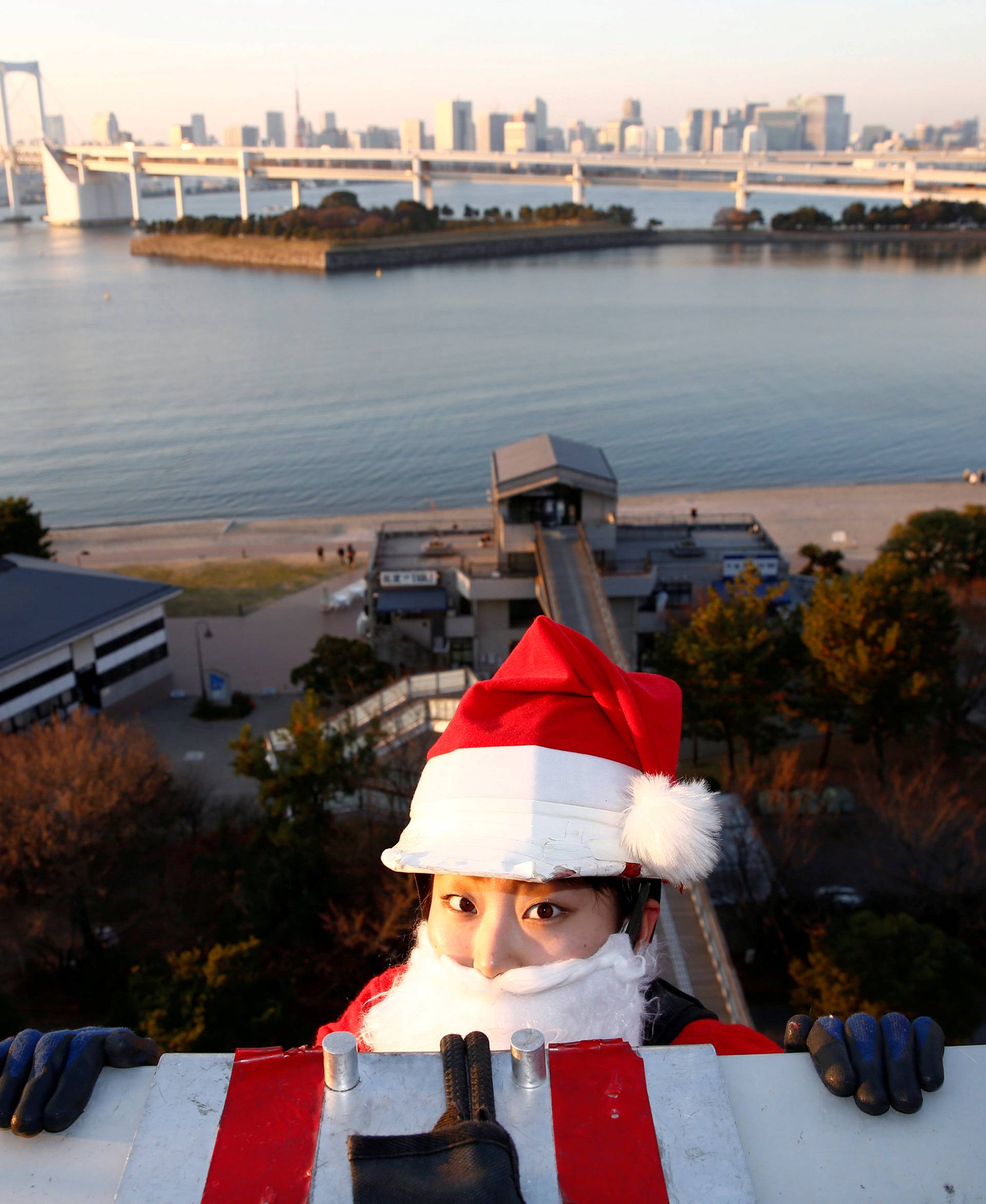 Female window cleaner dressed as Santa Claus prepares to clean a glass window at an event to celebrate the upcoming Christmas at DECKS Tokyo Beach in Tokyo