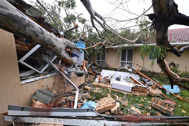 Debris lies at a damaged house by a fallen gum tree ahead of Tropical Cyclone Alfred's landfall, at Mudgeeraba on the Gold Coast