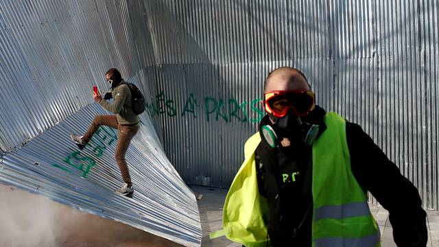 Protester wearing a yellow vest walks in front of demolished metal fencing during a demonstration by the "yellow vests" movement in Paris