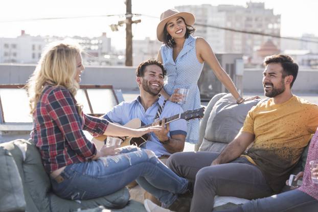 Friends having a rooftop party and playing guitar