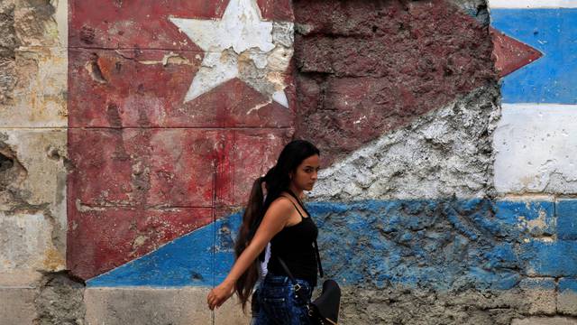 A woman walks in front of a mural of the Cuban flag in Havana, Cuba