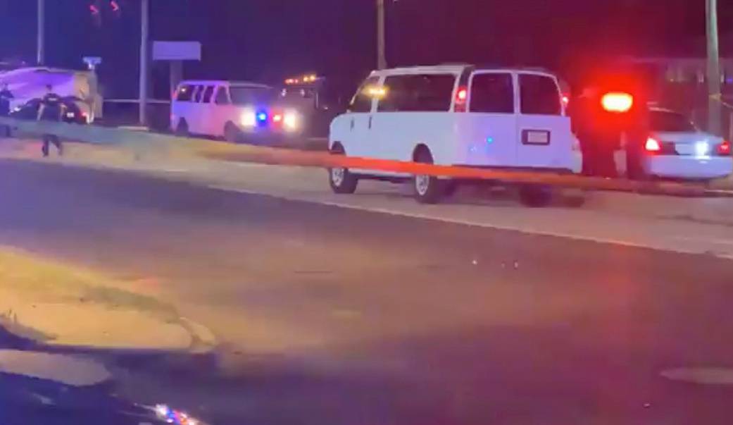 Police personnel and their vehicles are seen near the scene in the aftermath of a drive-by shooting at a liquor store in Shreveport, Louisiana