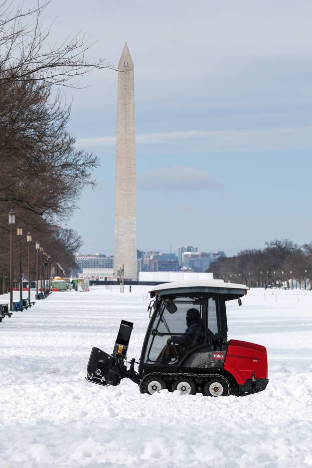 A person riding a snow blower drives near the Washington Monument after a winter storm in Washington