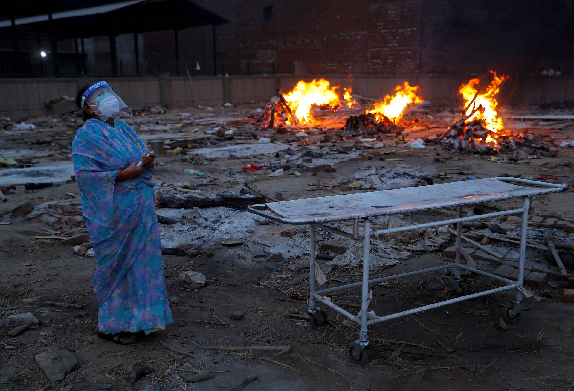 A woman cries during the cremation of her husband, who died from the coronavirus disease (COVID-19), at a crematorium in New Delhi