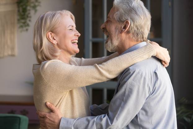 Happy senior couple relax dancing at home together