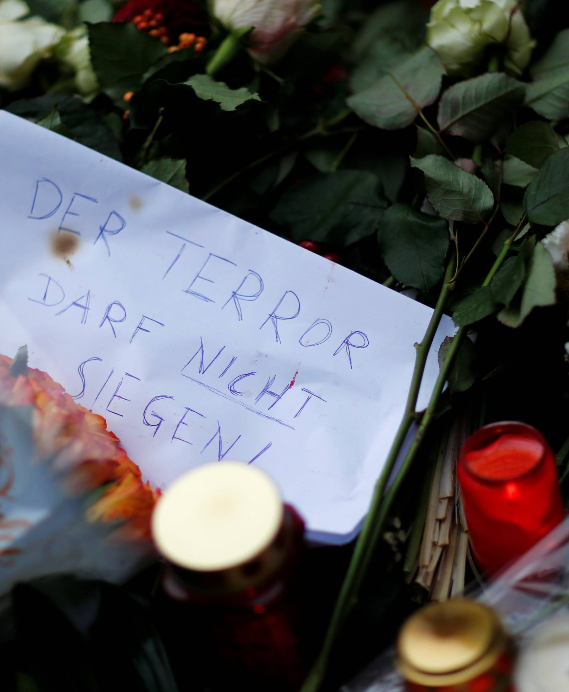Flowers, candles and a note saying "The terror can not prevail" are placed near the Christmas market in Berlin