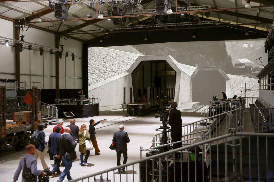 Journalists walk in front of mock gates of the NEAT Gotthard Base Tunnel inside the event hall for the upcoming opening ceremony near the town of Erstfeld