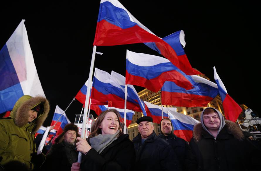 People wave Russian flags during a rally and concert marking the fourth anniversary of Russia's annexation of the Crimea region, at Manezhnaya Square in central Moscow