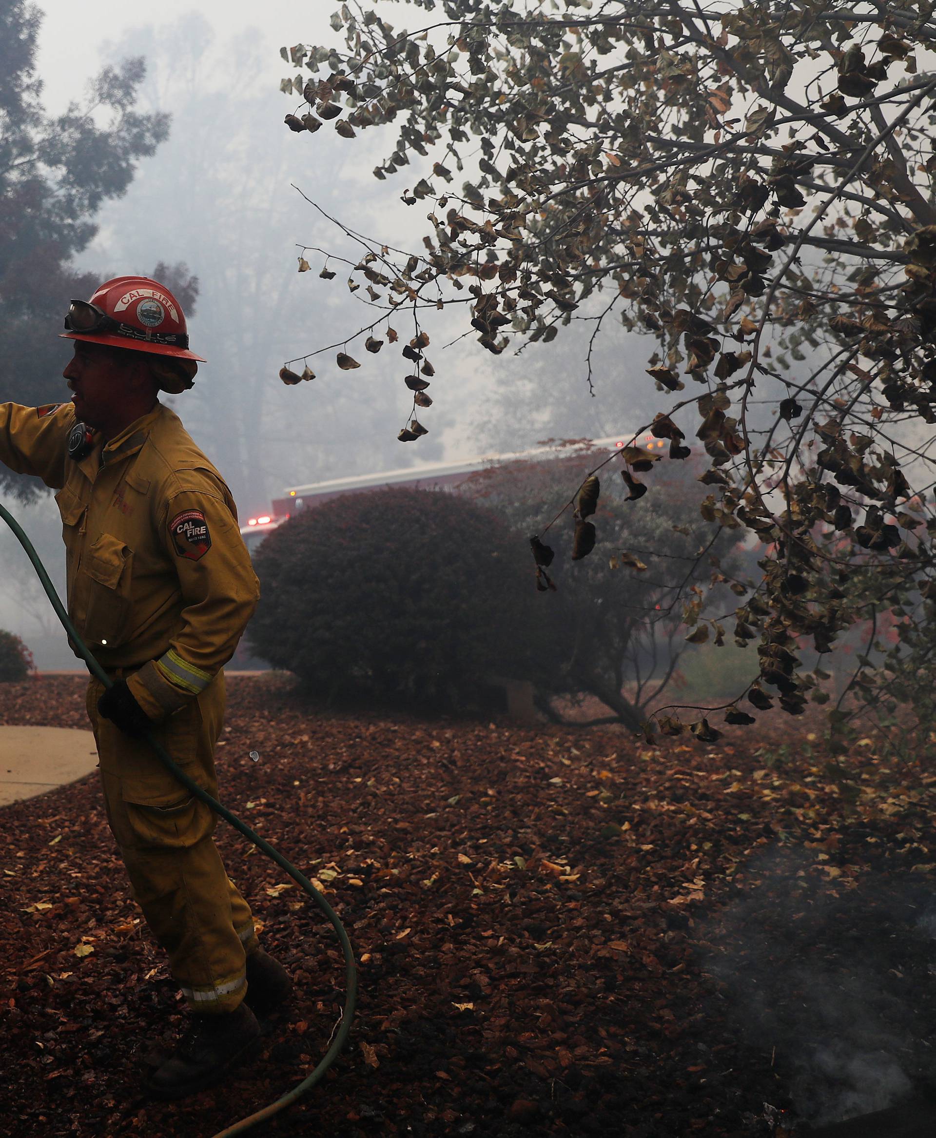 A Cal Fire firefighter hoses a smoldering home while battling the Camp Fire in Paradise