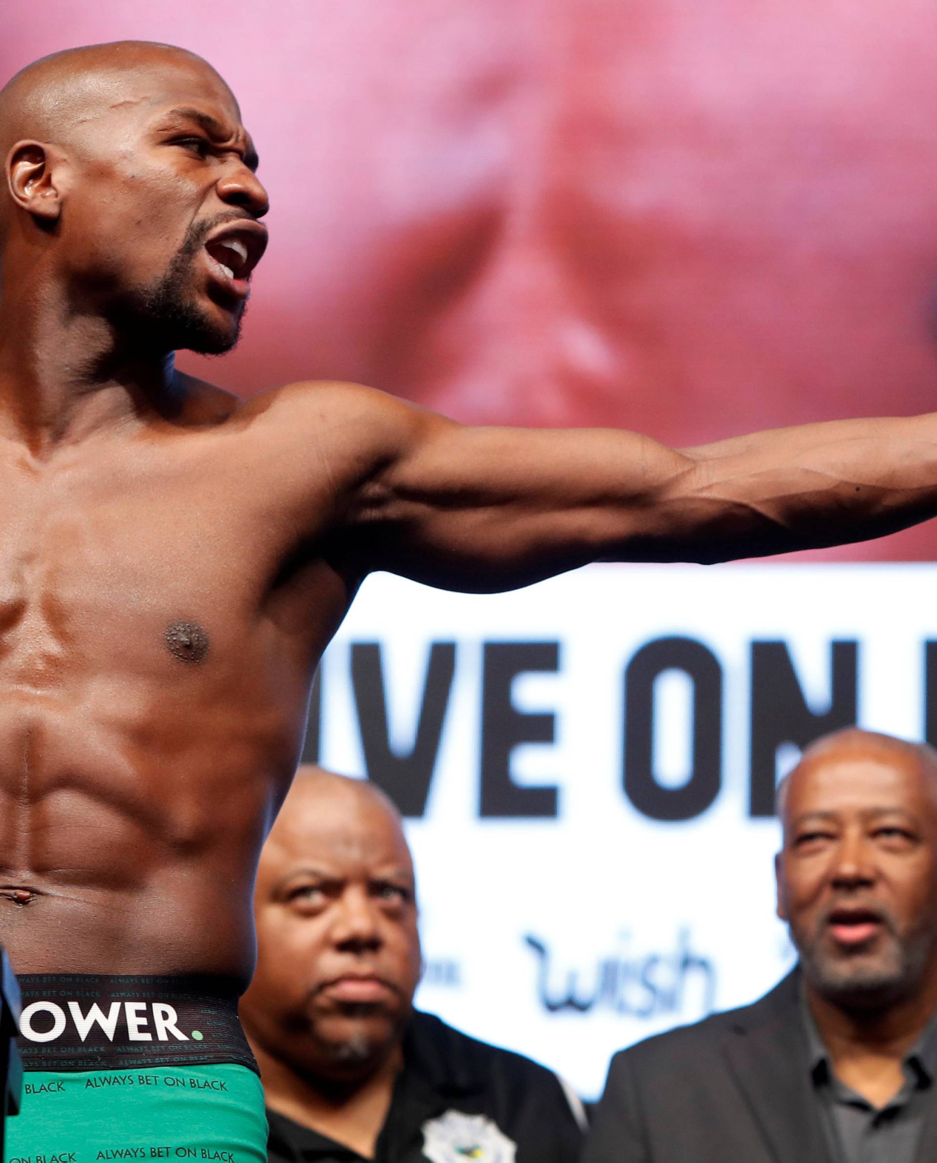 Undefeated boxer Floyd Mayweather Jr. of the U.S. points to UFC lightweight champion Conor McGregor of Ireland  during his official weigh-in at T-Mobile Arena in Las Vegas