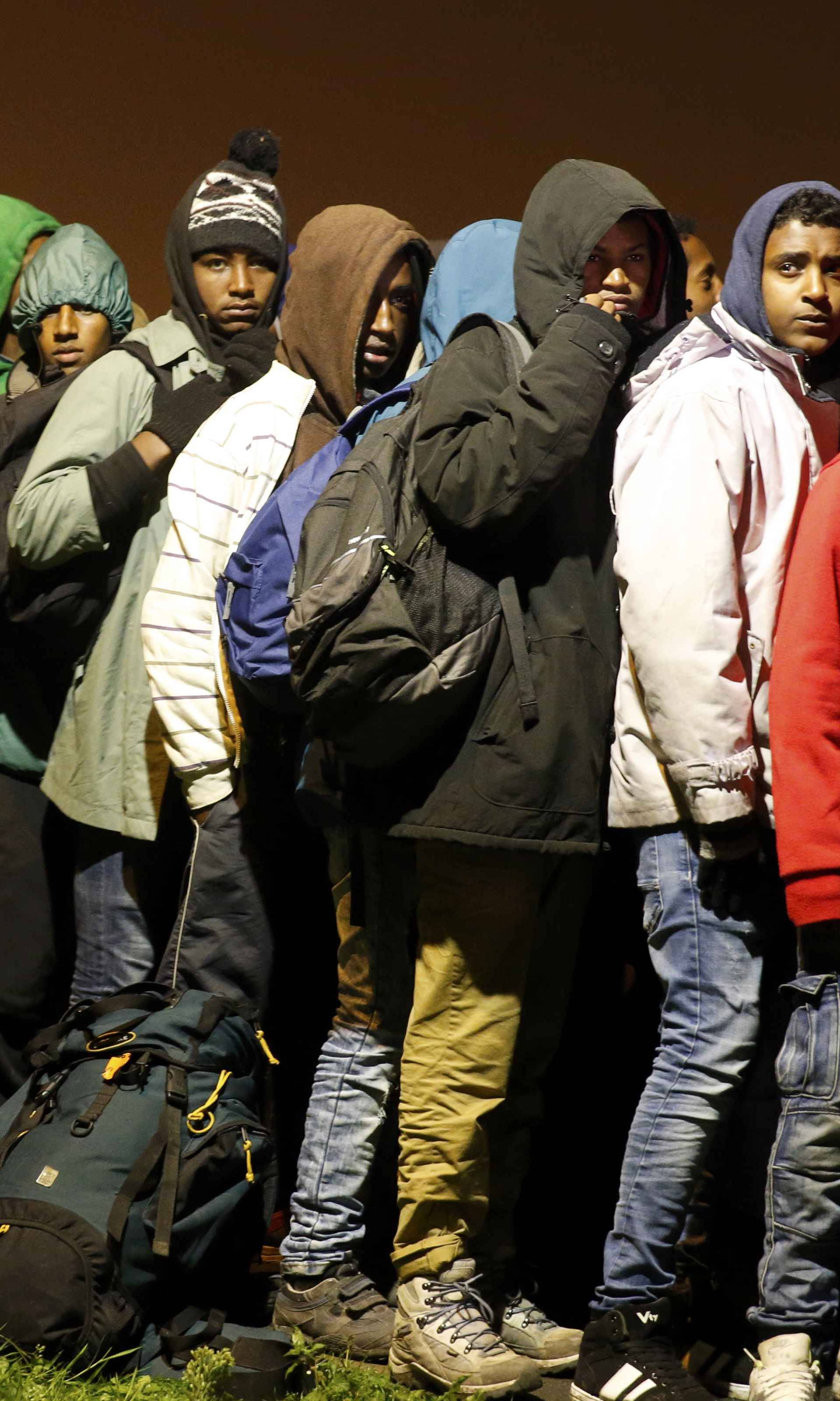 Migrants with their belongings queue as their evacuation and transfer to reception centers in France, and the dismantlement of the camp called the "Jungle" in Calais starts