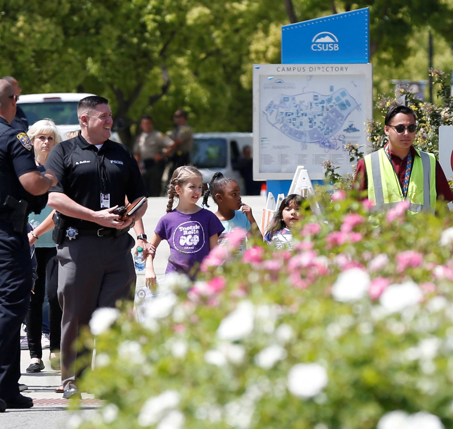 Police officers escort students from a campus of California State University - San Bernardino, where they were evacuated after a shooting at North Park Elementary School