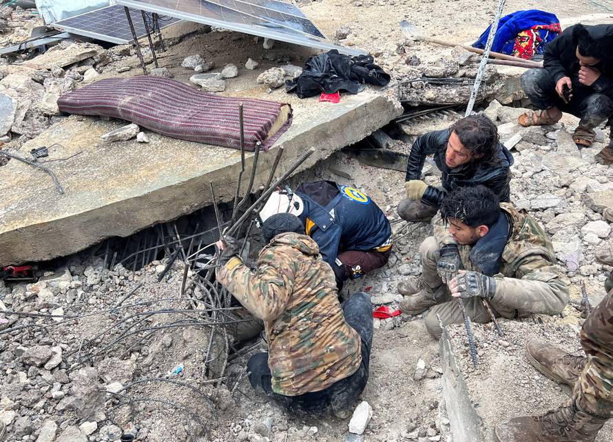 Rescuers search for survivors under the rubble, following an earthquake, in rebel-held town of Jandaris