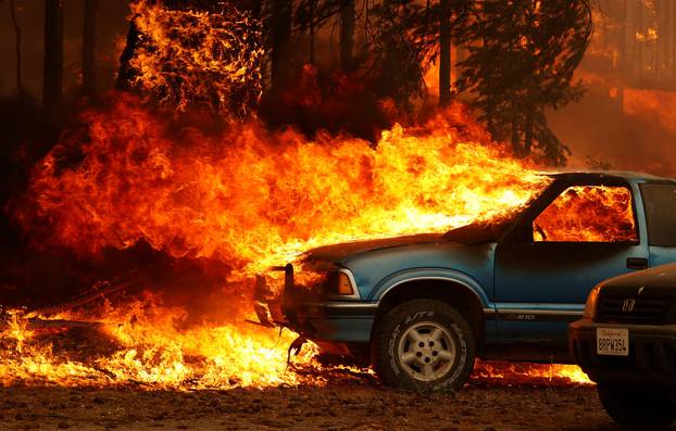 Wind-driven flames shoot horizontally out of the windshield of a car on fire at the Dixie Fire, a wildfire near the town of Greenville