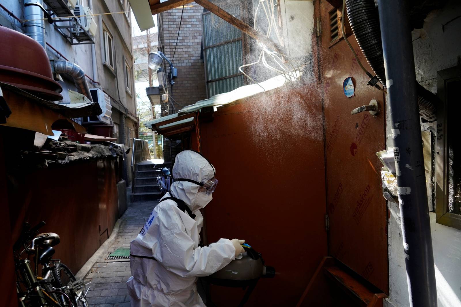 An employee from a disinfection service company sanitizes a shack at a shanty area in Seoul