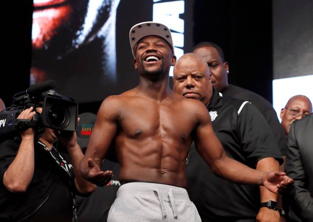 Undefeated boxer Floyd Mayweather Jr. of the U.S. laughs after posing with UFC lightweight champion Conor McGregor of Ireland during their official weigh-in at T-Mobile Arena in Las Vegas