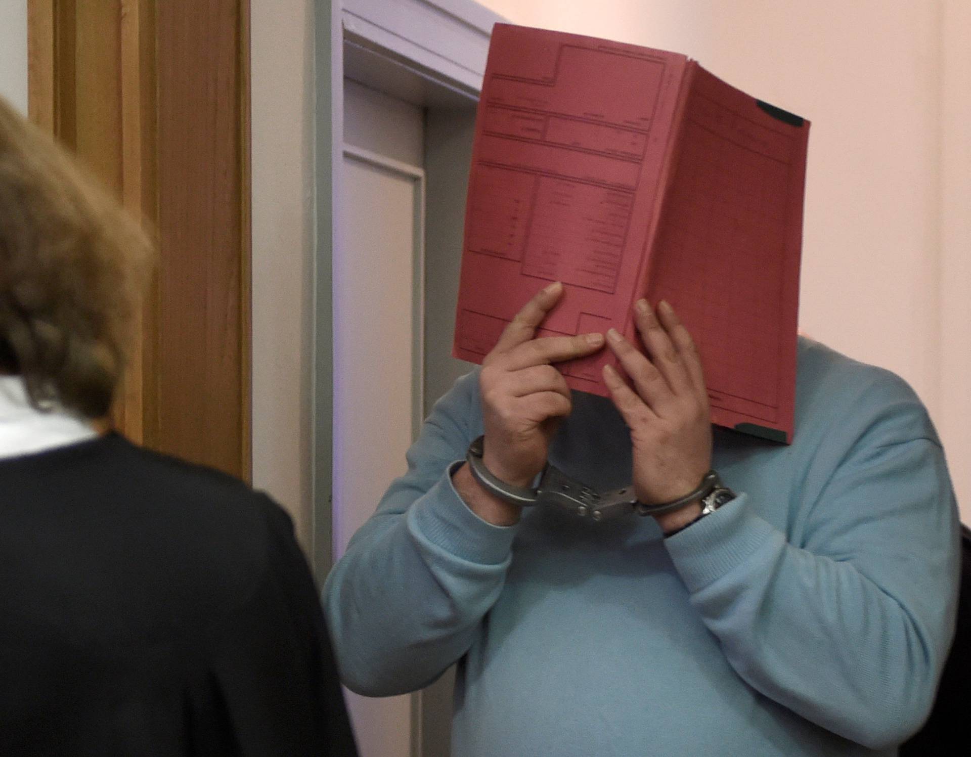 FILE PHOTO: Former nurse Niels H. masks his face with a folder on his arrival in the courtroom in Oldenburg