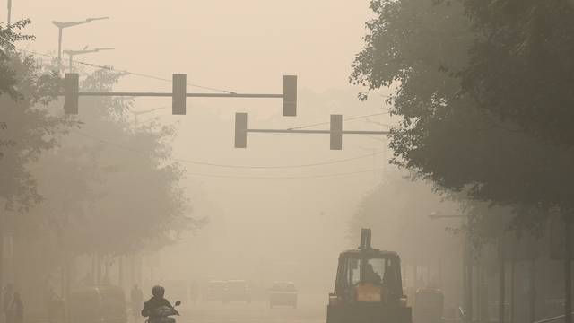 A bulldozer is seen on a road, on a smoggy morning, in New Delhi