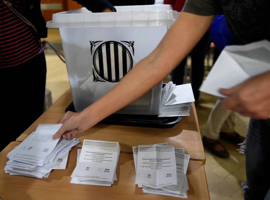 Poll workers count ballots after polls closed at a polling station for the banned independence referendum in Barcelona