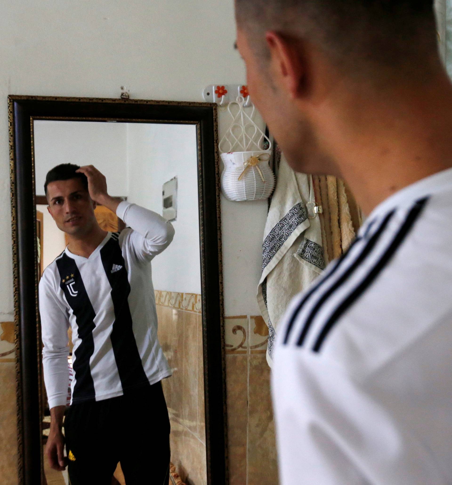 Biwar Abdullah, 25, an Iraqi Kurdish local footballer, who looks like the football player Cristiano Ronaldo, looks at a mirror at his home in the district of Soran, northeast of Erbil