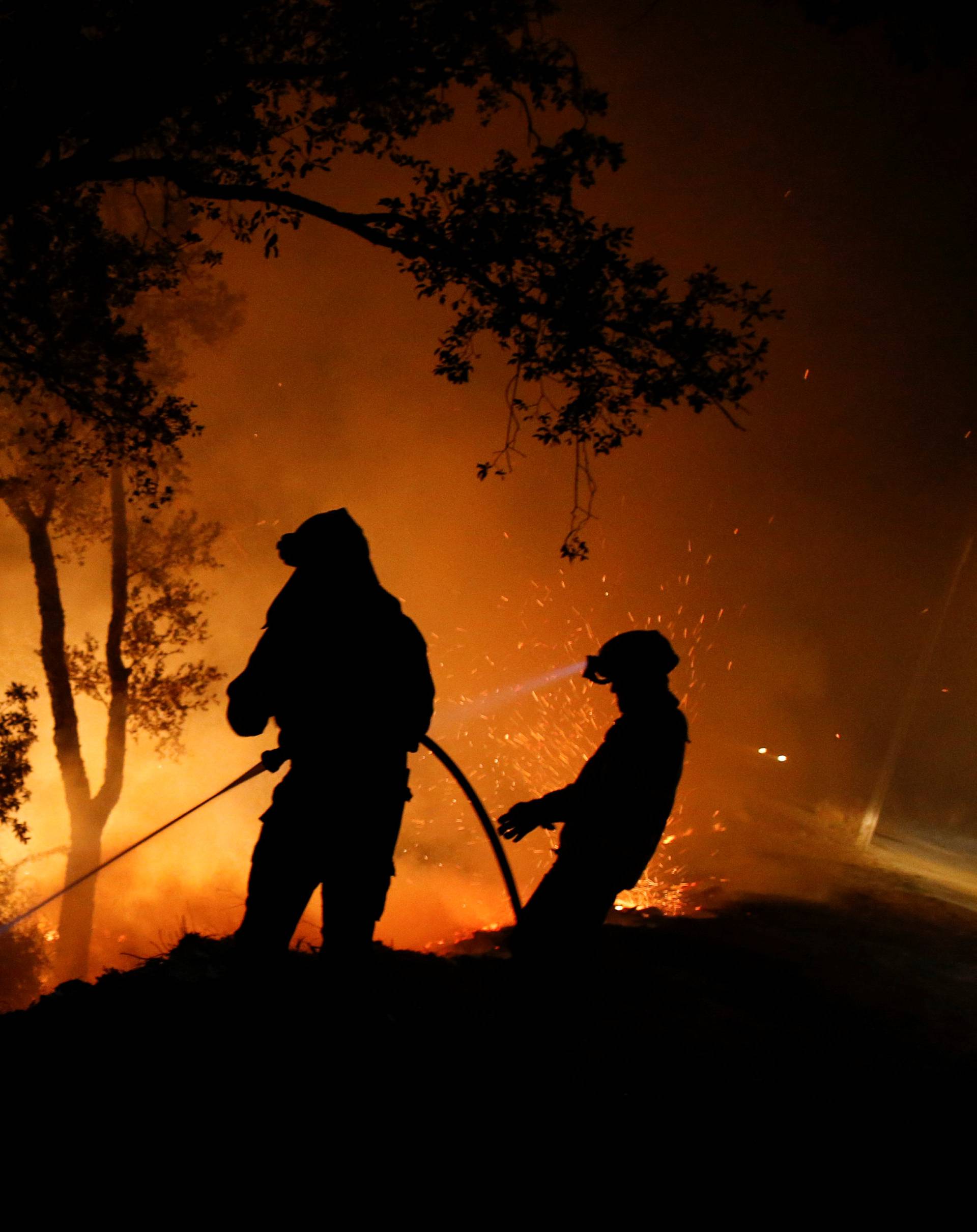 Firefighters work to extinguish flames from a forest fire in Cabanoes near Lousa