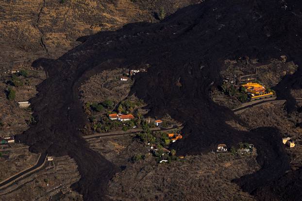 Lava flows around houses following the eruption of a volcano on the Island of La Palma