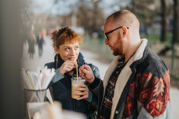 Couple sharing a drink outdoors in a cheerful setting