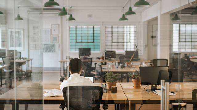 Rearview,Of,A,Young,Businessman,Sitting,Alone,At,His,Desk