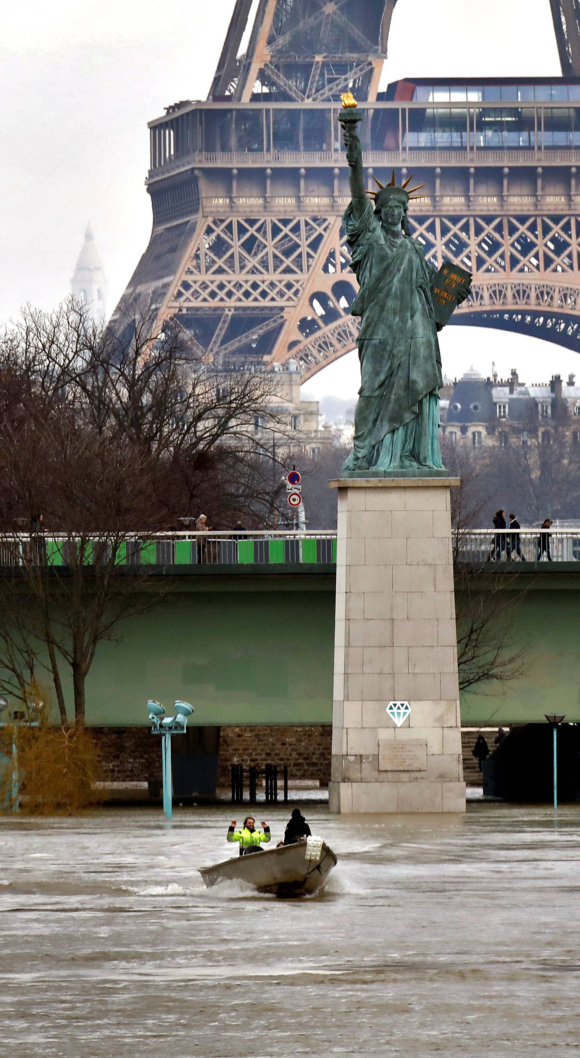 A boat on the flooded River Seine passes the Statue of Liberty replica in Paris