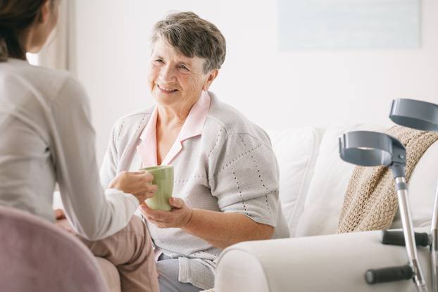 Young,Caregiver,Serving,He,Tea,To,The,Older,Woman
