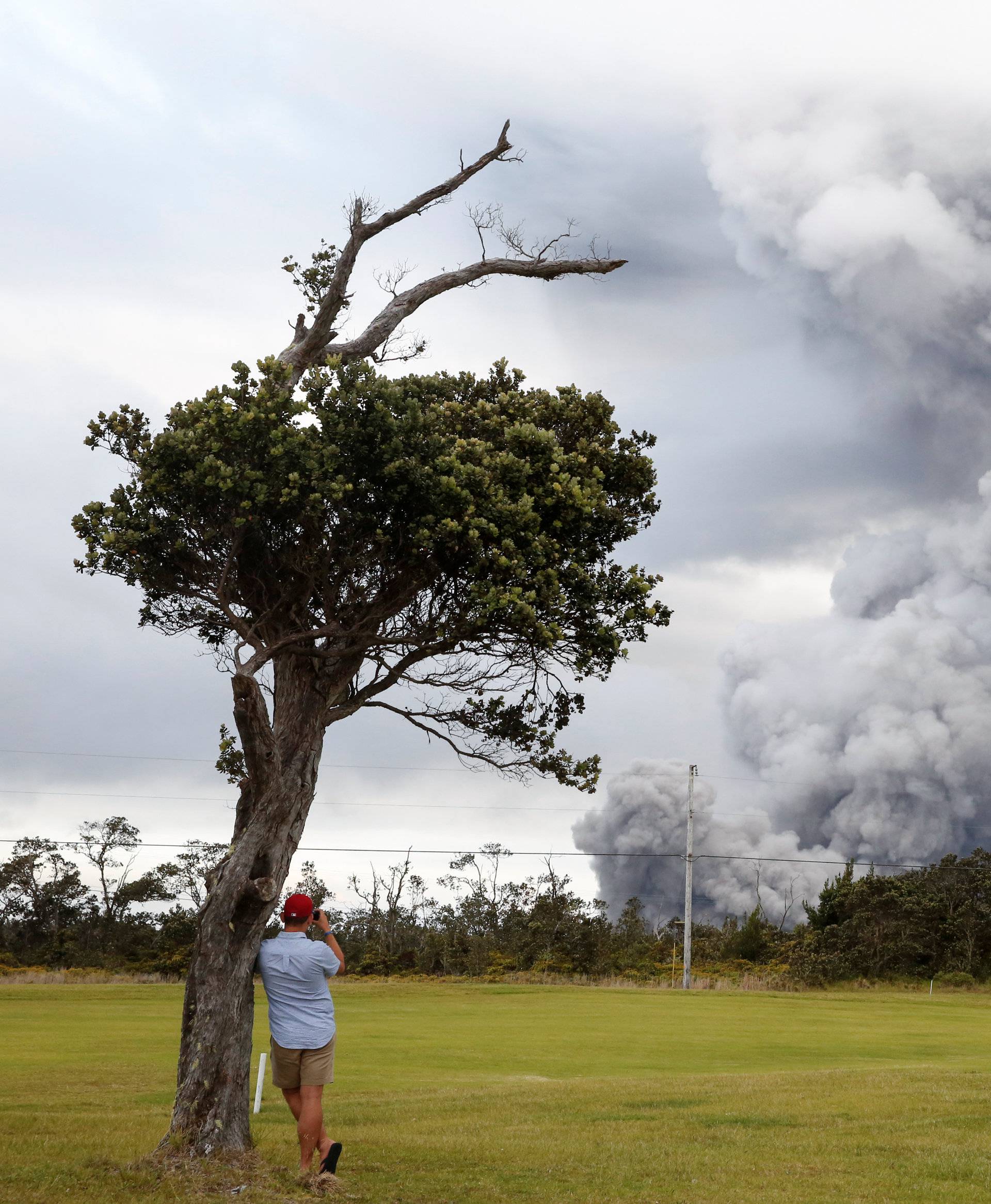 A man watches as ash erupts from the Halemaumau crater near the community of Volcano