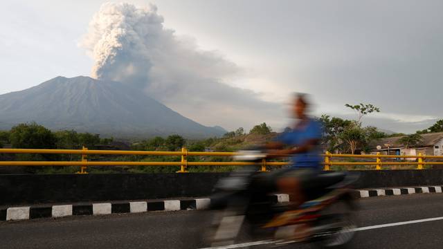 A motorist rides across a bridge as Mount Agung volcano erupts near Kubu in Bali
