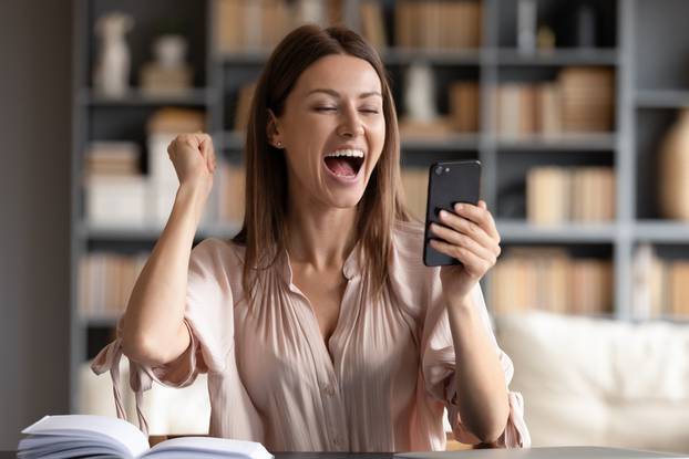 Close,Up,Overjoyed,Woman,Looking,At,Phone,Screen,,Celebrating,Success,